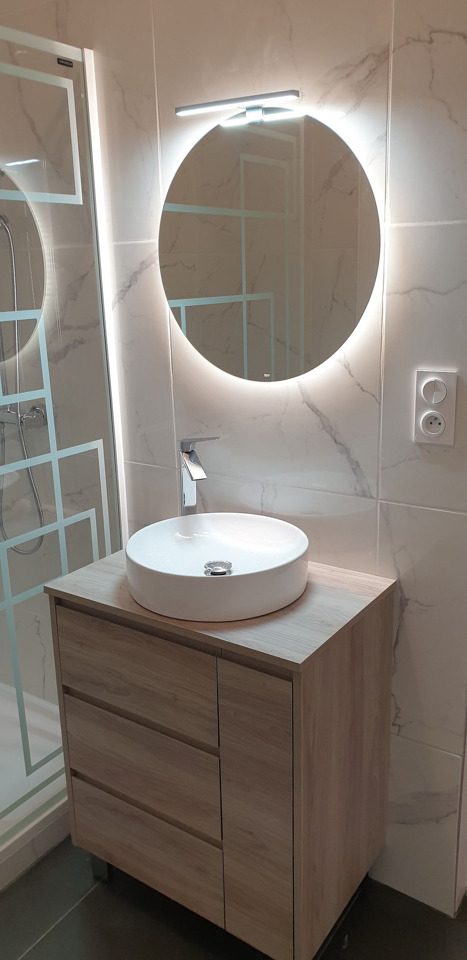 Miroir rond lumineux et carrelage à effet marbre
