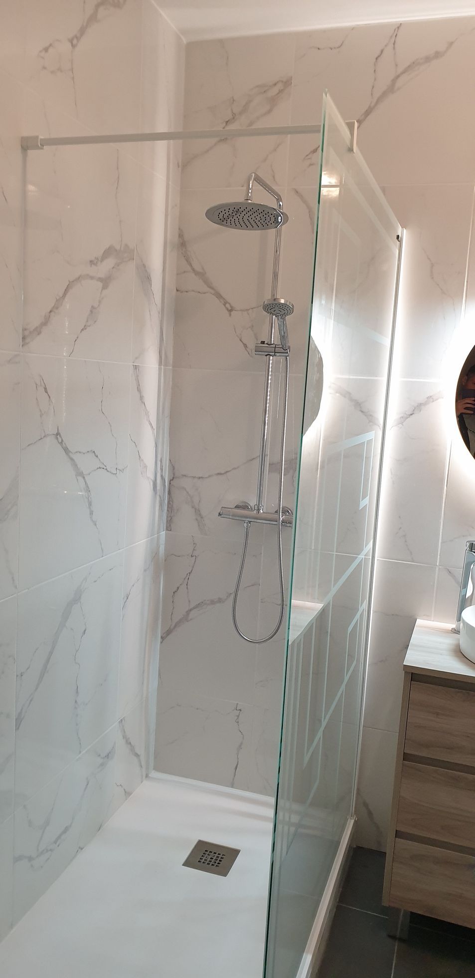 Douche moderne avec du carrelage en marbre et une paroi vitrée