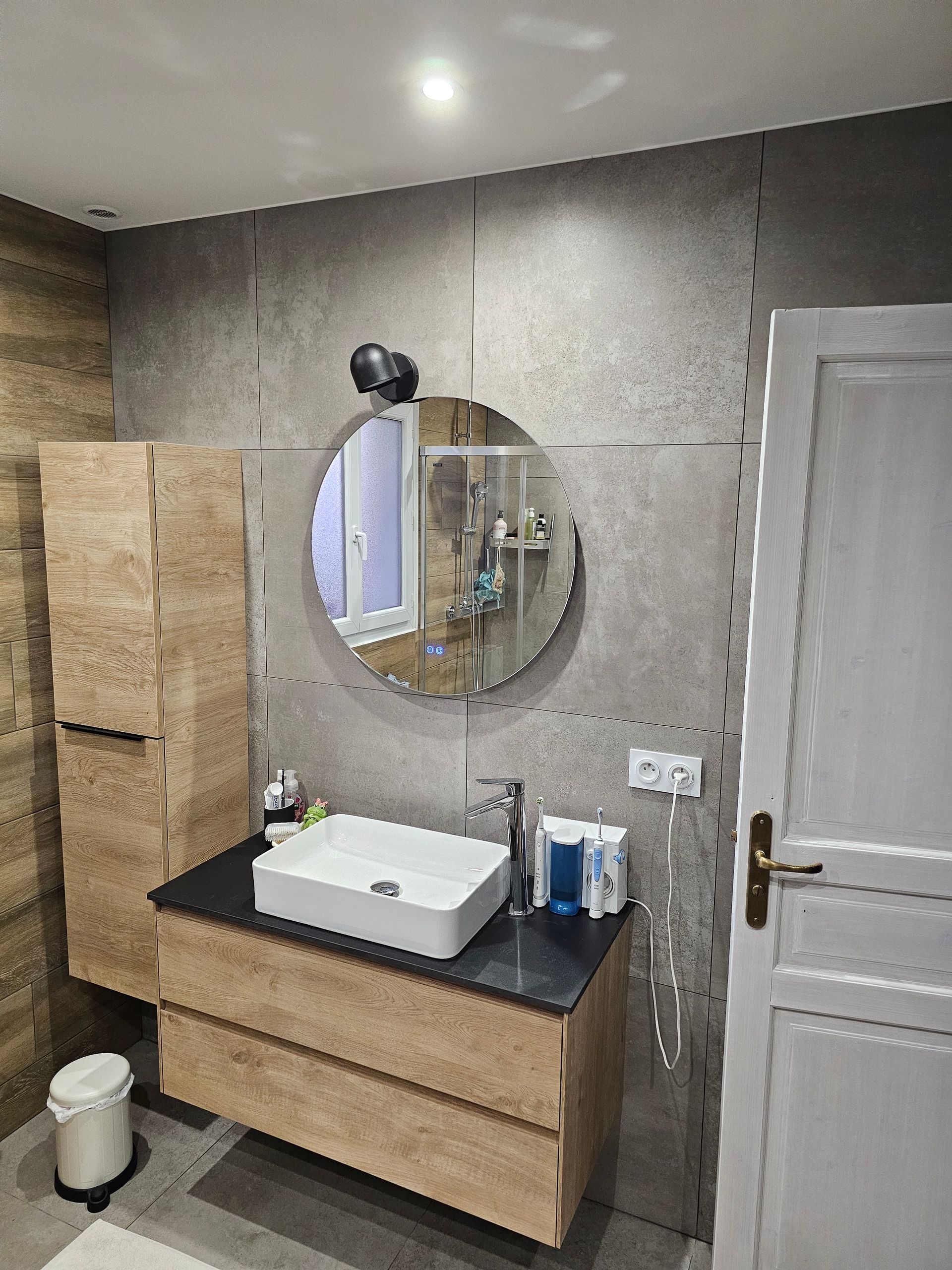 Meuble vasque avec un miroir rond et un éclairage intégré