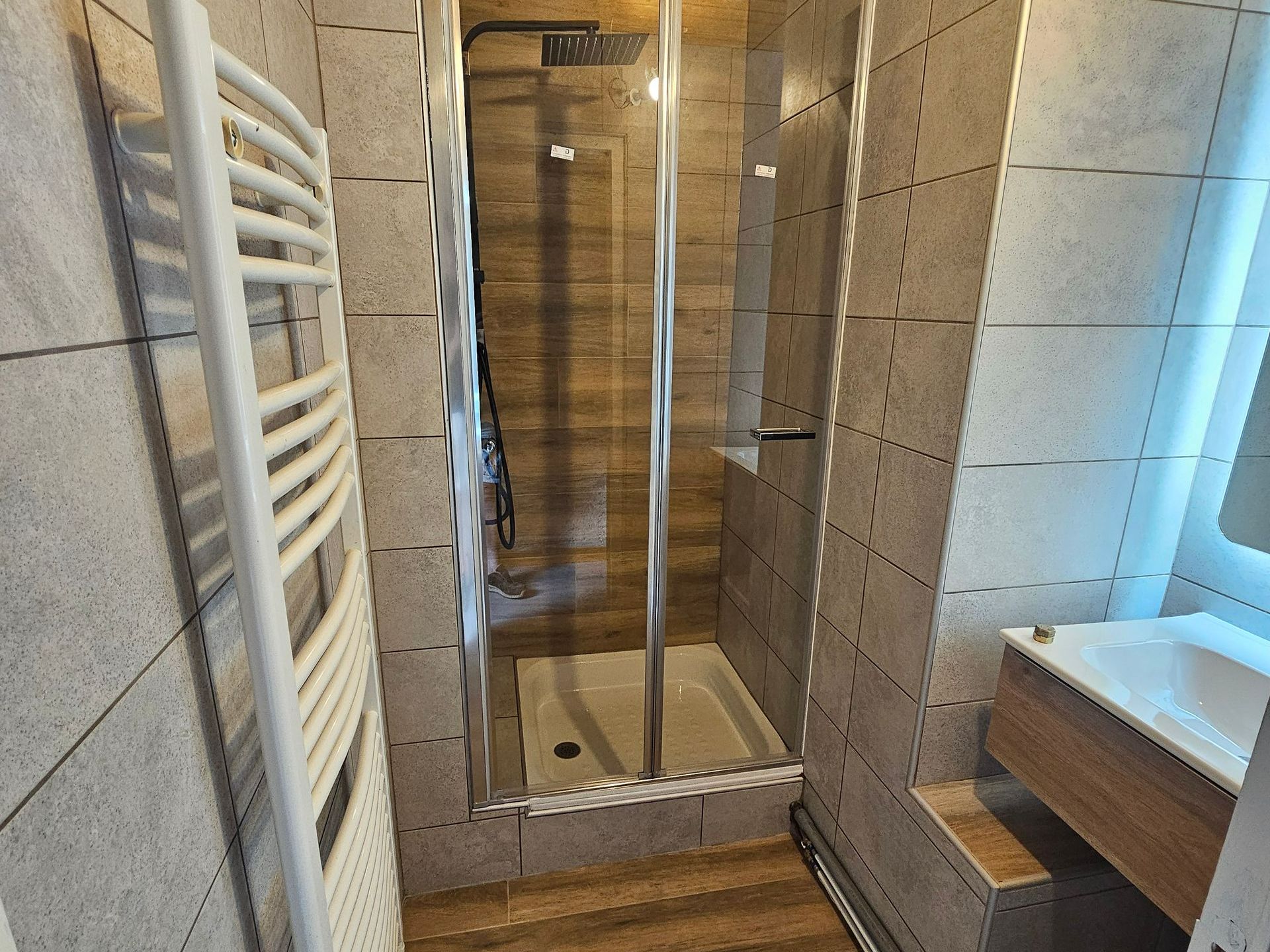 Salle de bains avec un sol en bois et des murs carrelés