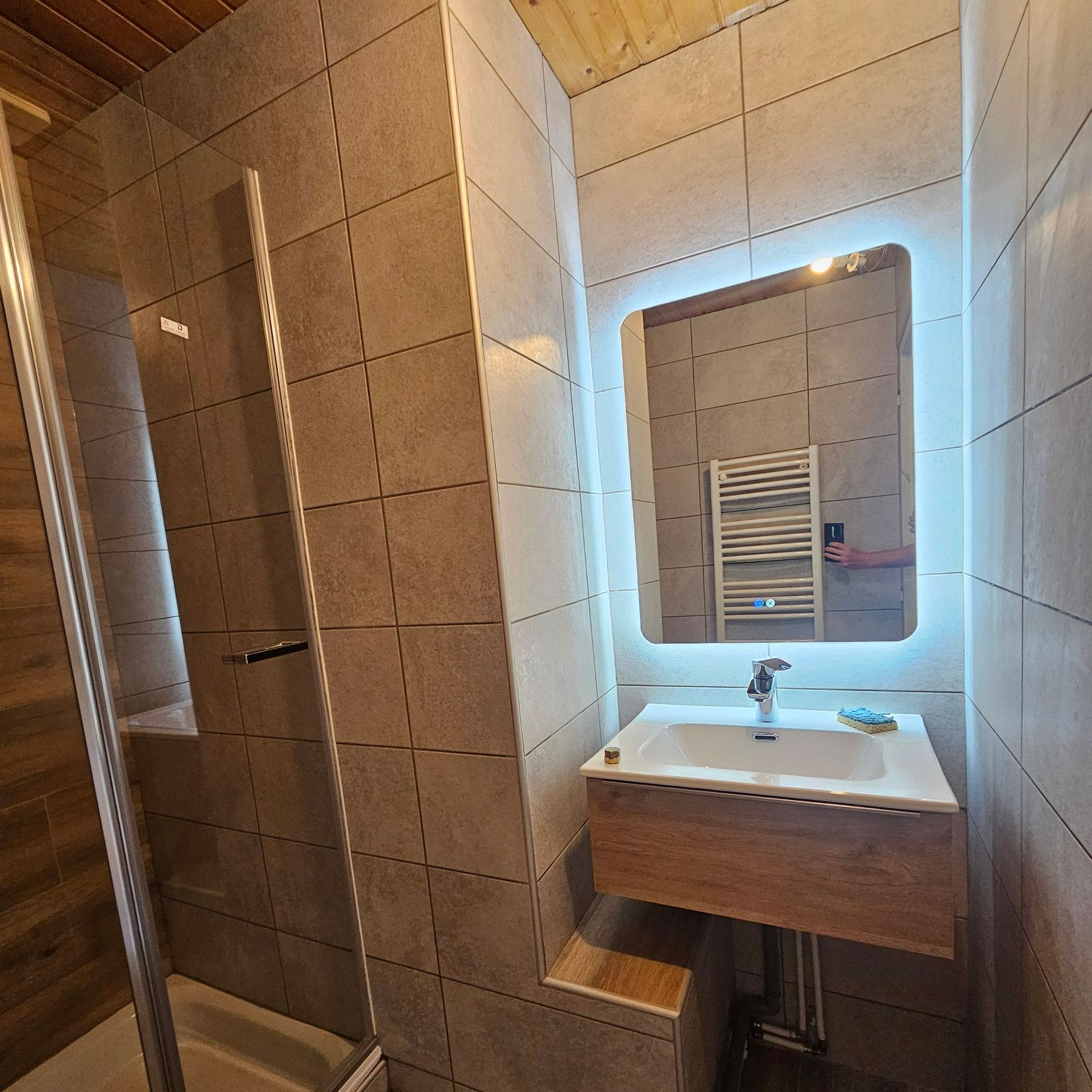 Salle de bains avec du carrelage mural et un éclairage intégré