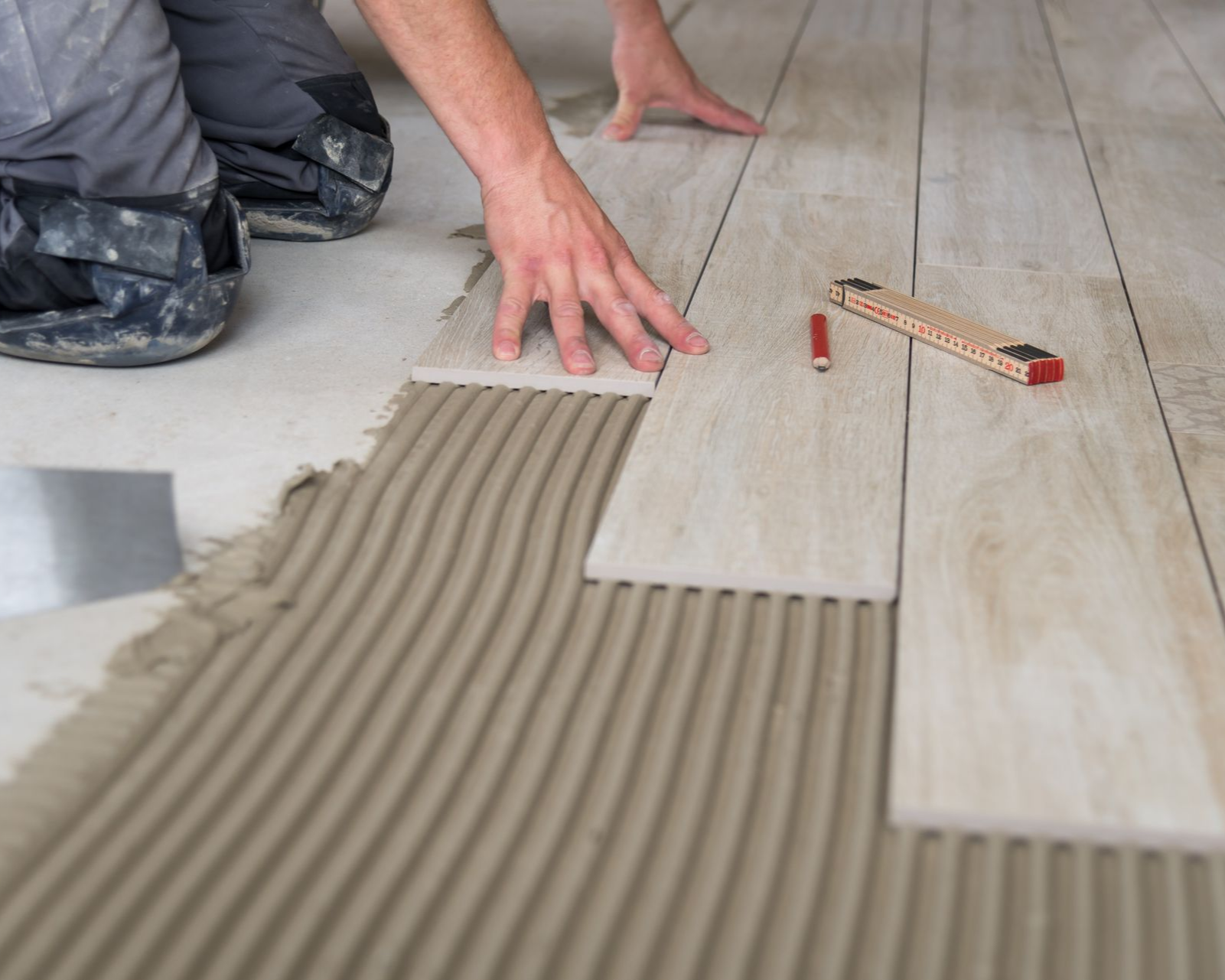 Artisan qui colle du carrelage au sol