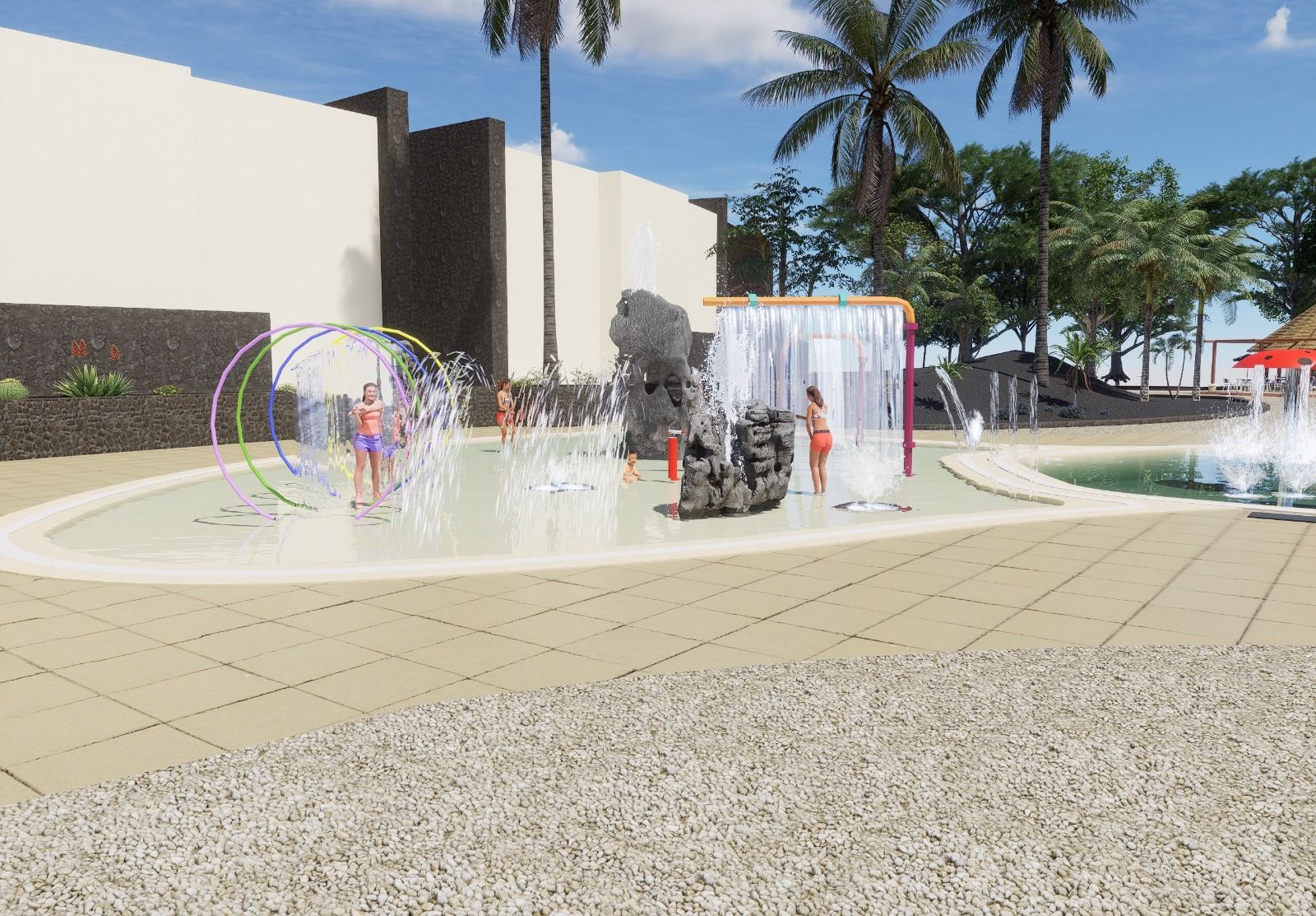 Niños jugando en un parque acuático con fuentes de agua; entorno al aire libre con palmeras y un edificio de color claro.