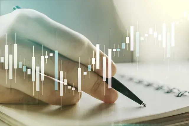 Escritura a mano en un cuaderno con un bolígrafo; superpuesto con un gráfico del mercado financiero.