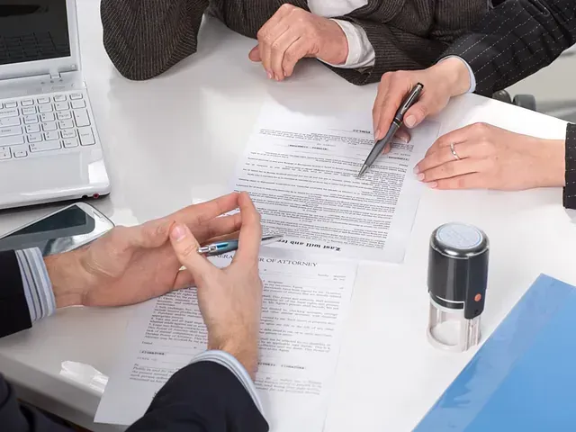 Personas vestidas de negocios revisan documentos en una mesa, uno señala con un bolígrafo, sugiriendo una negociación de contrato.