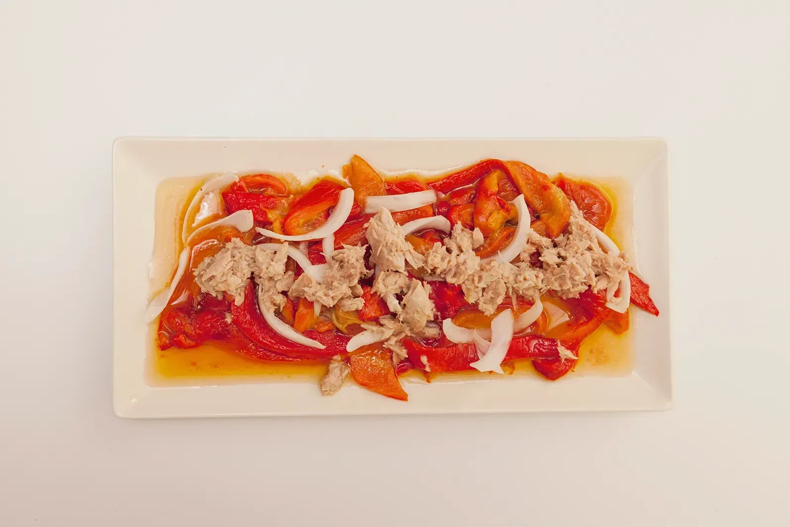 Ensalada de pimientos rojos asados con atún desmenuzado y cebolla blanca en rodajas.
