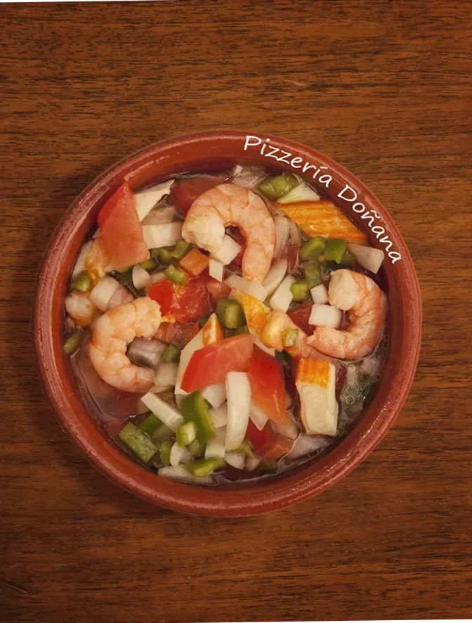 Un plato horneado con queso fundido y salsa cremosa en un bol redondo, servido sobre un plato blanco.