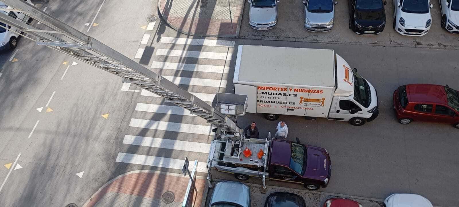 Vista aérea de una intersección urbana con varios coches, una furgoneta blanca y pasos de peatones pintados.