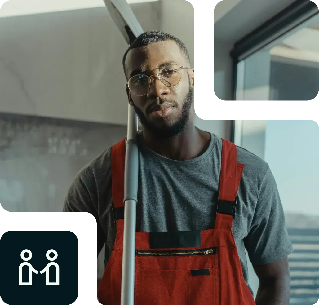 Un hombre con mono rojo sostiene una fregona y mira a la cámara.