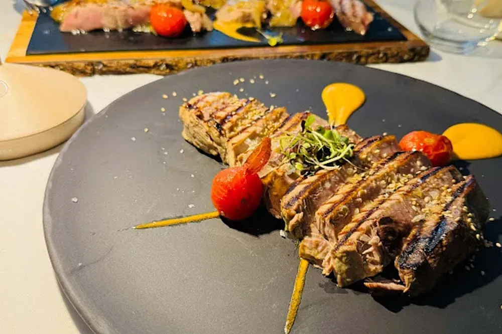Un plato negro sobre una mesa con un filete y tomates.