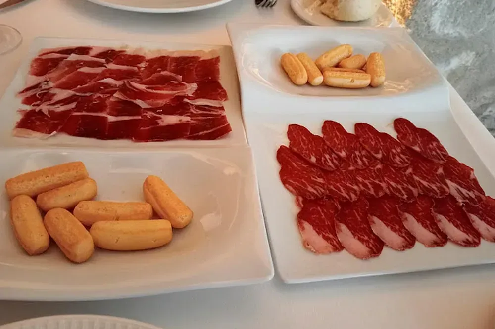 Sobre una mesa hay tres platos de carne y galletas.