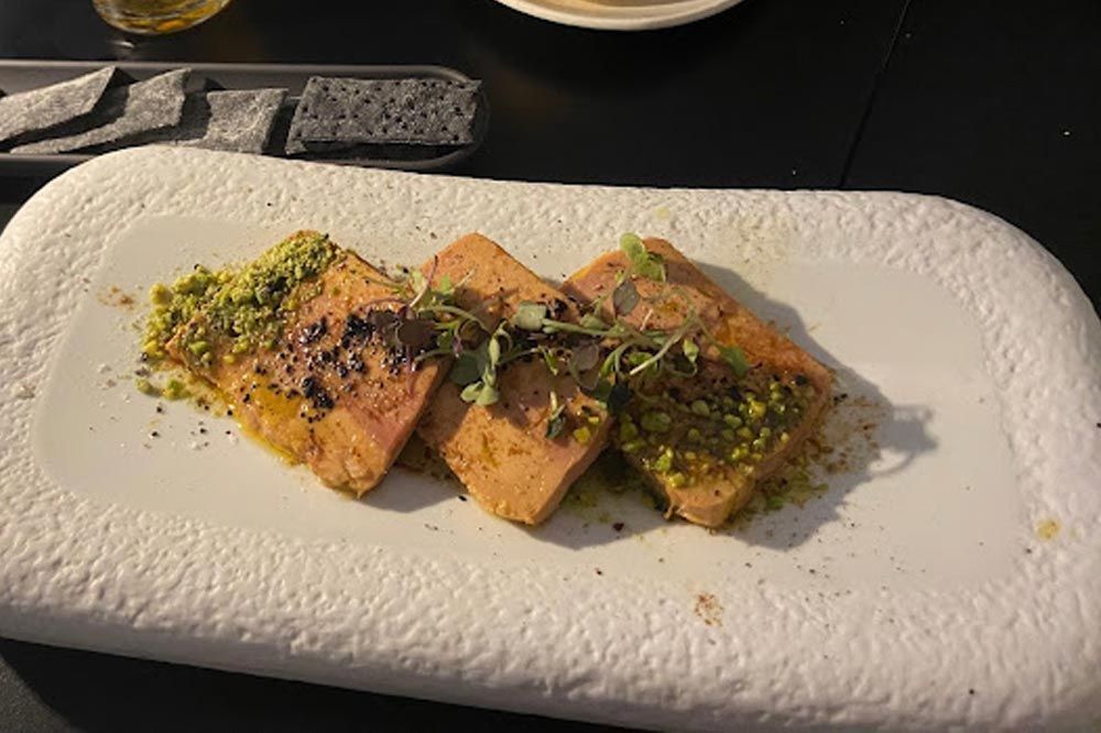Un plato blanco cubierto con carne y verduras sobre una mesa.