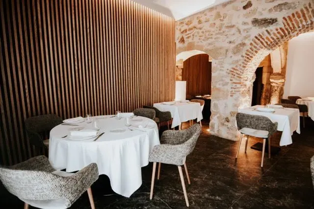 Un restaurante con mesas y sillas y una pared de piedra.