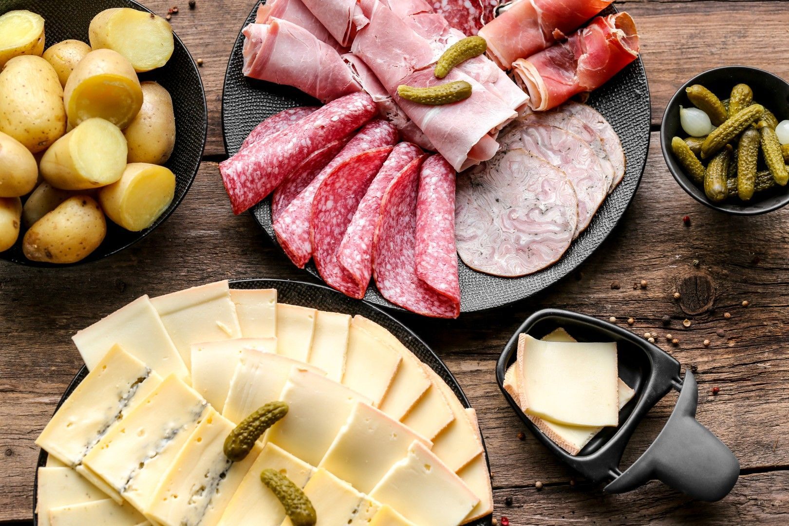 Plateau de raclette avec assortiment de charcuteries, viandes tranchées, fromage, pommes de terre et