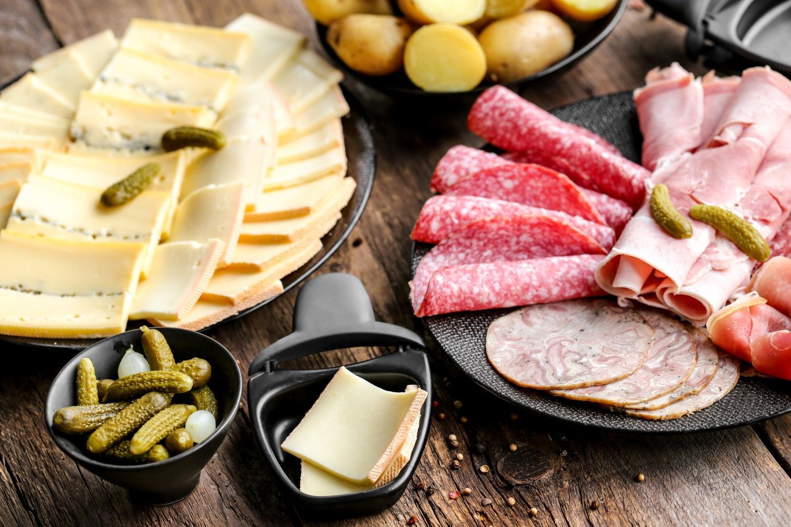 Plateau de raclette composé de fromages, de charcuteries variées, de cornichons et de pommes de terr