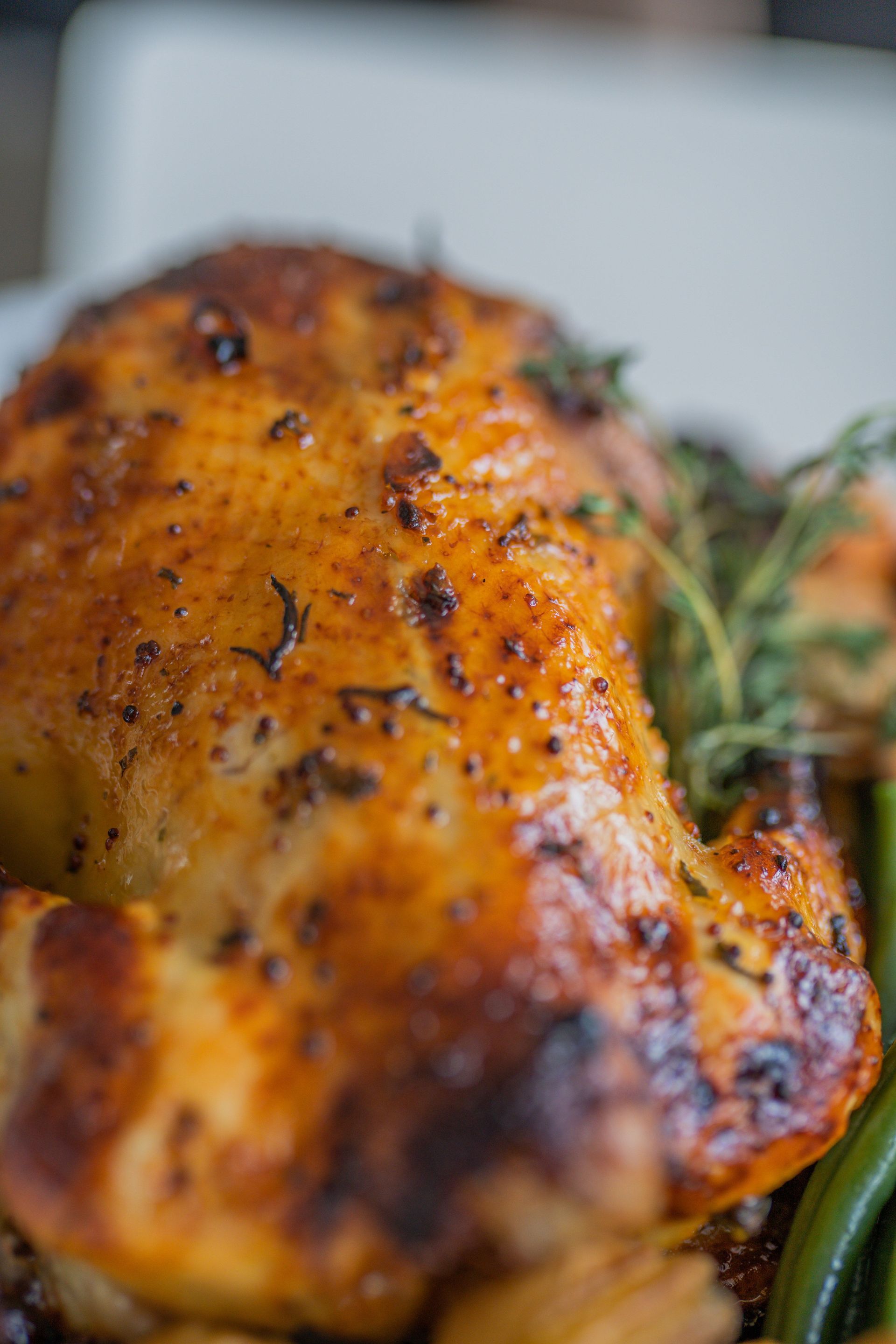 Poulet rôti doré à souhait, présenté sur un plat avec des herbes aromatiques et des légumes.