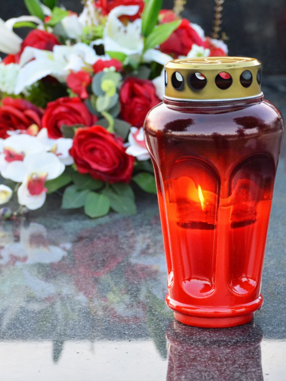 Lanterne et composition florale sur une tombe.