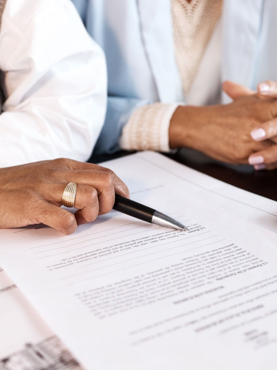 Une main tenant un stylo posé sur un contrat.