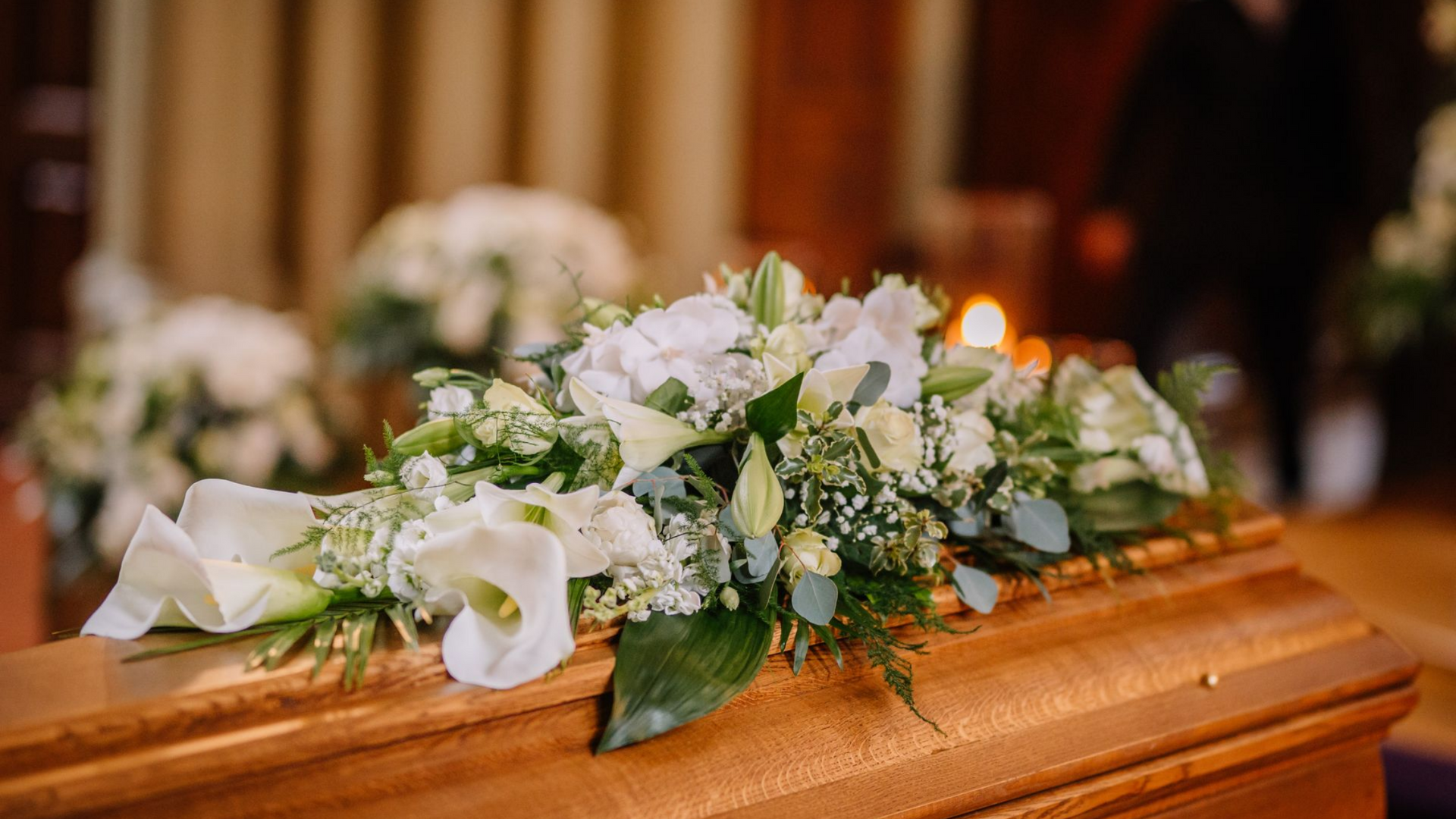 Un cercueil recouvert de fleurs blanches.