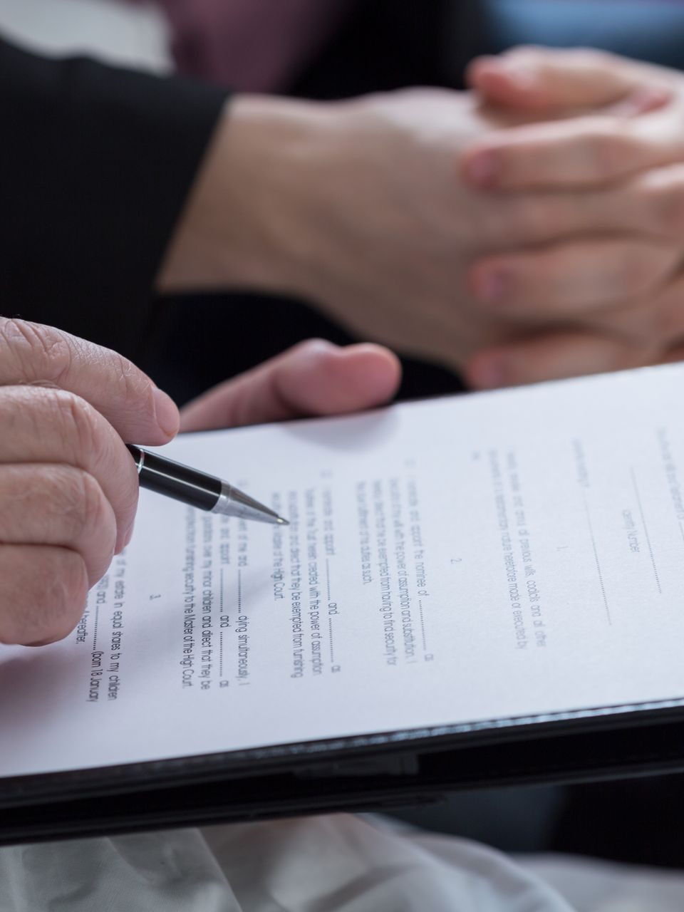 Personnes dont l'une d'elles tient un stylo au-dessus d'un document.