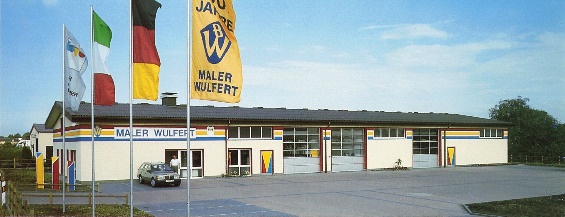 Fertigstellung der neuen Halle Ein Auto steht vor einem Gebäude mit der Aufschrift „Maler Import“
