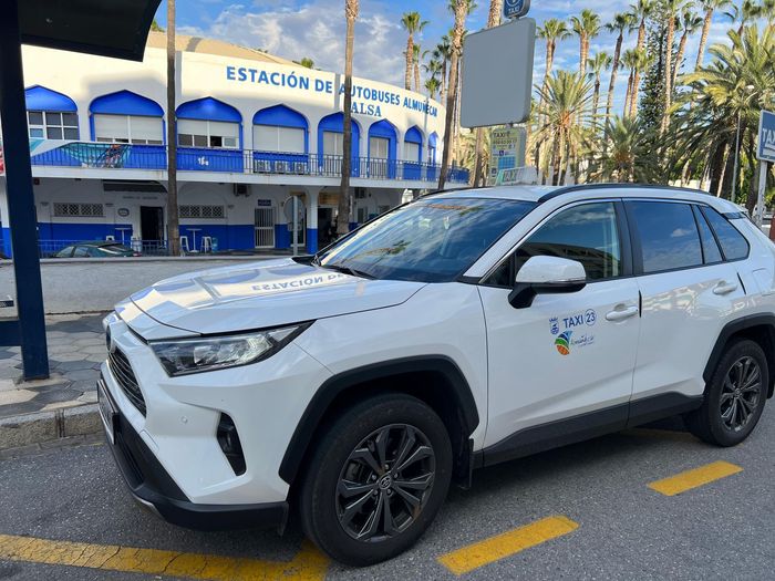Una camioneta blanca está estacionada al costado de la carretera frente a un edificio.