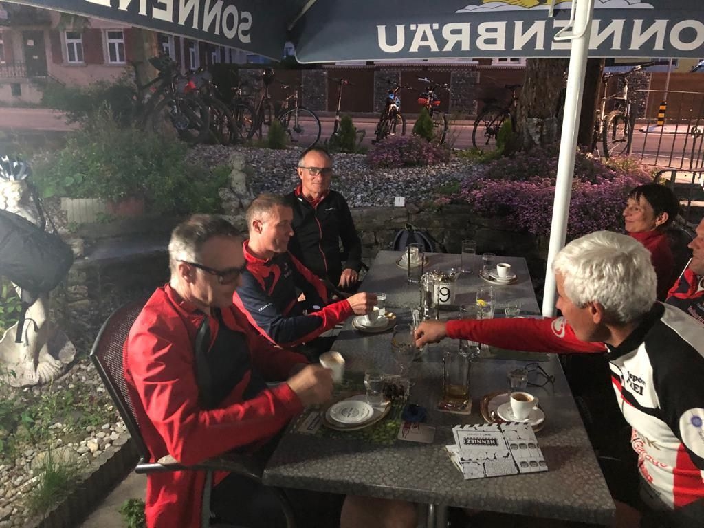 Eine Gruppe von Leuten sitzt unter einem Sonnenschirm an einem Tisch.