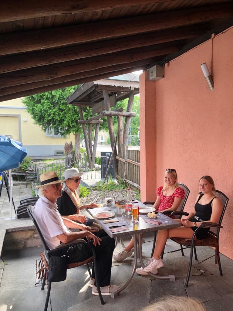 Eine Gruppe von Leuten sitzt an einem Tisch auf einer Terrasse.