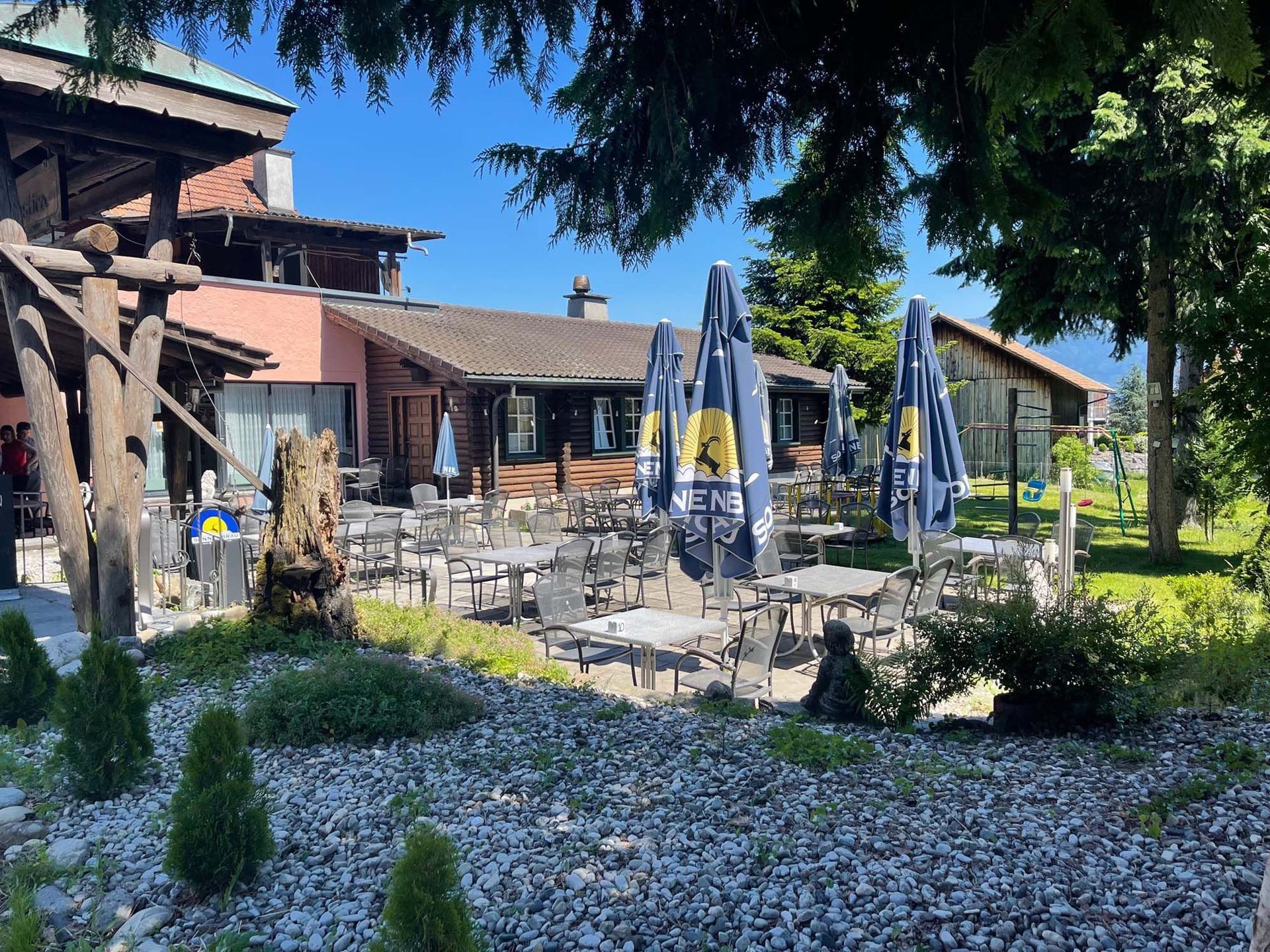 Ein Restaurant mit Tischen und Stühlen und Sonnenschirmen davor.