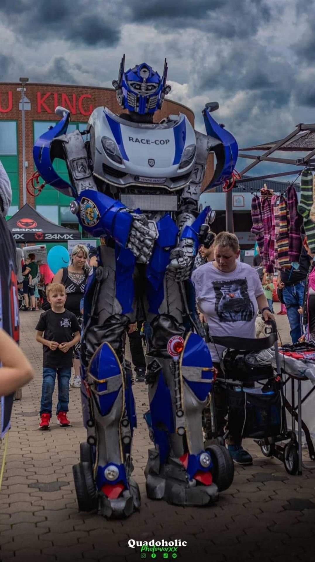 Ein Mann in einem Roboterkostüm steht vor einem Gebäude mit der Aufschrift „J King“