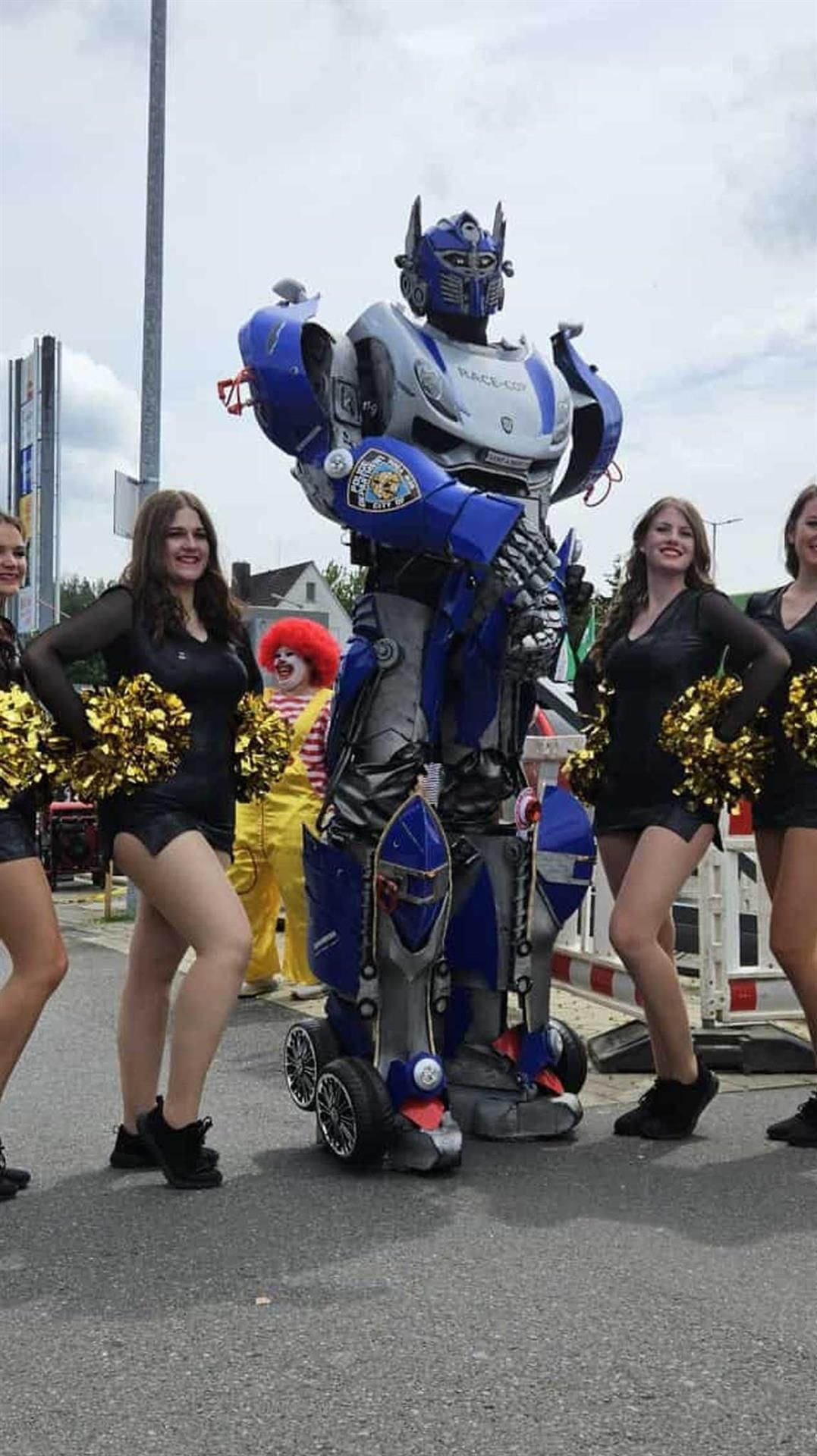 Eine Gruppe Cheerleader steht neben einem Roboterkostüm