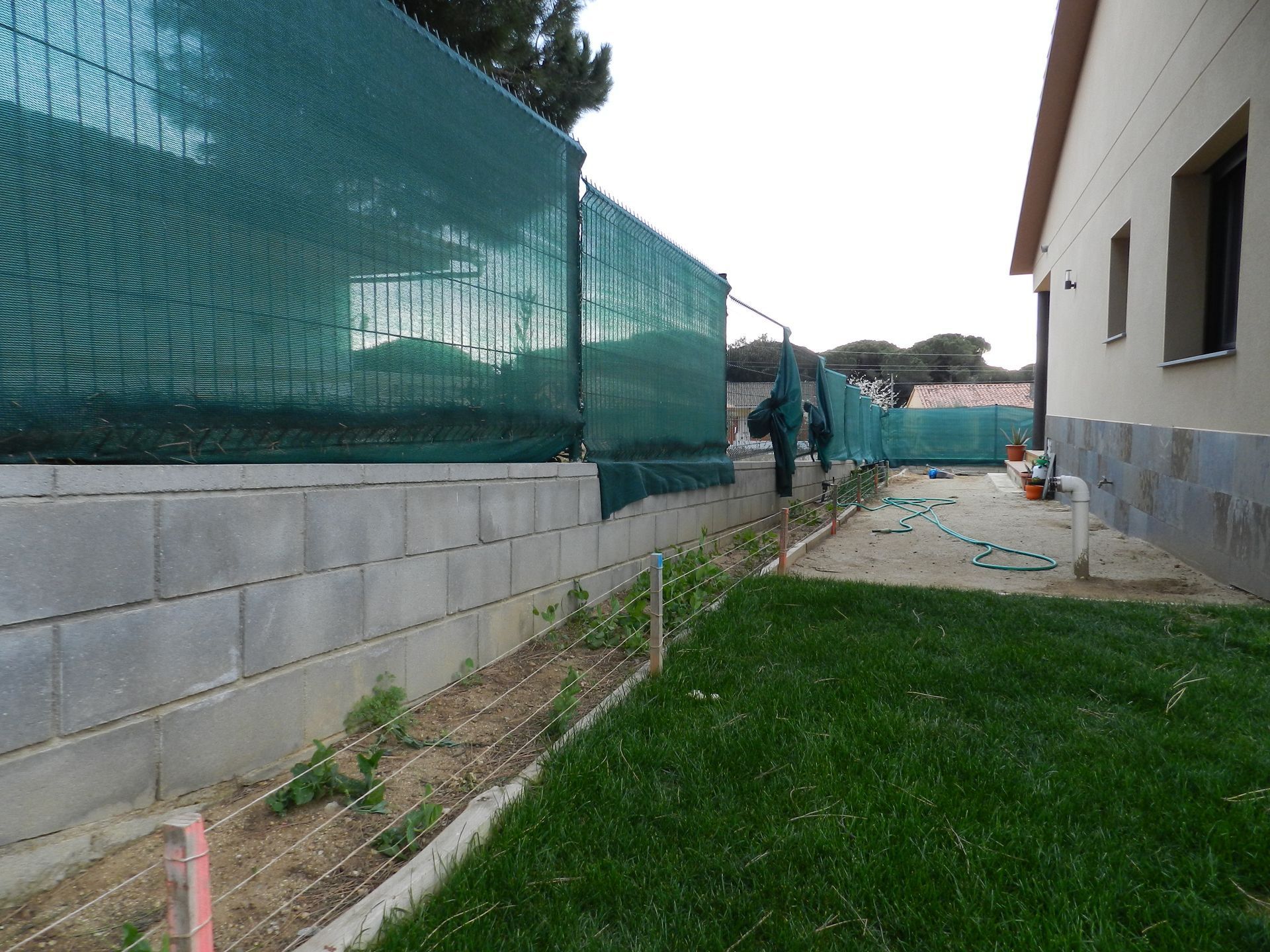 Un patio trasero con una valla y una casa al fondo.