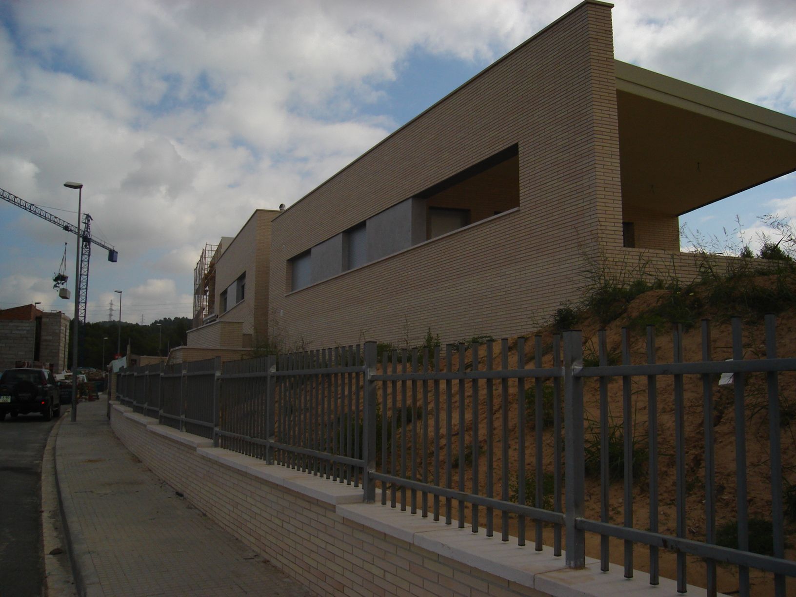 Un edificio con una valla alrededor y una grúa al fondo.