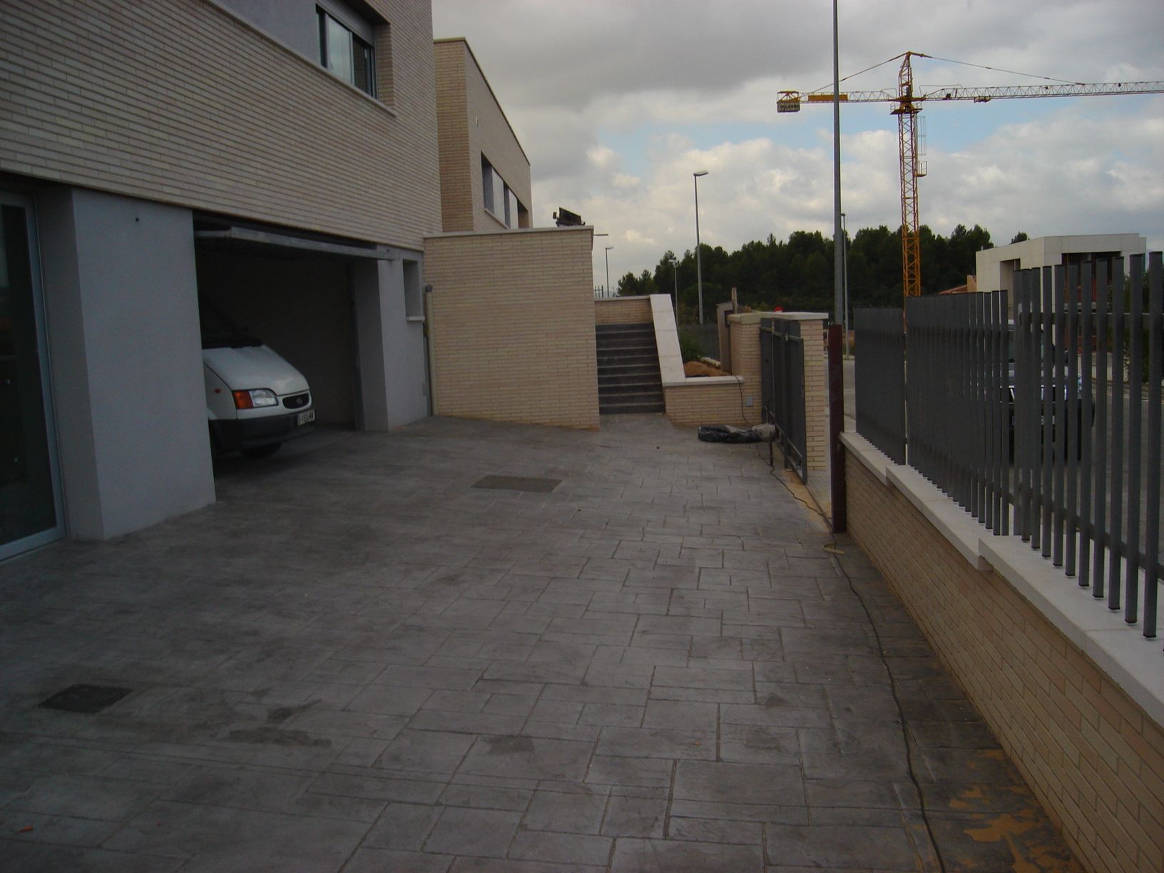 Un coche está aparcado en una entrada junto a un edificio.