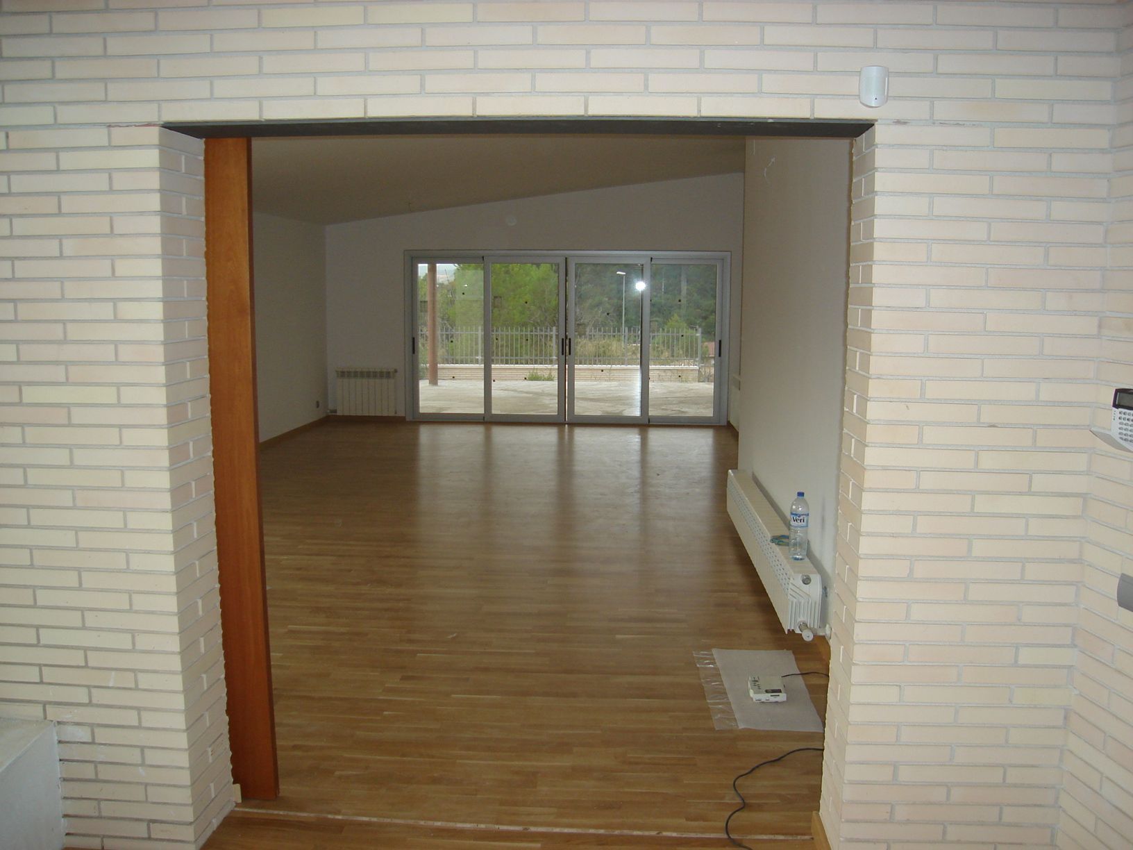 Una habitación vacía con una pared de ladrillos y puertas corredizas de vidrio.