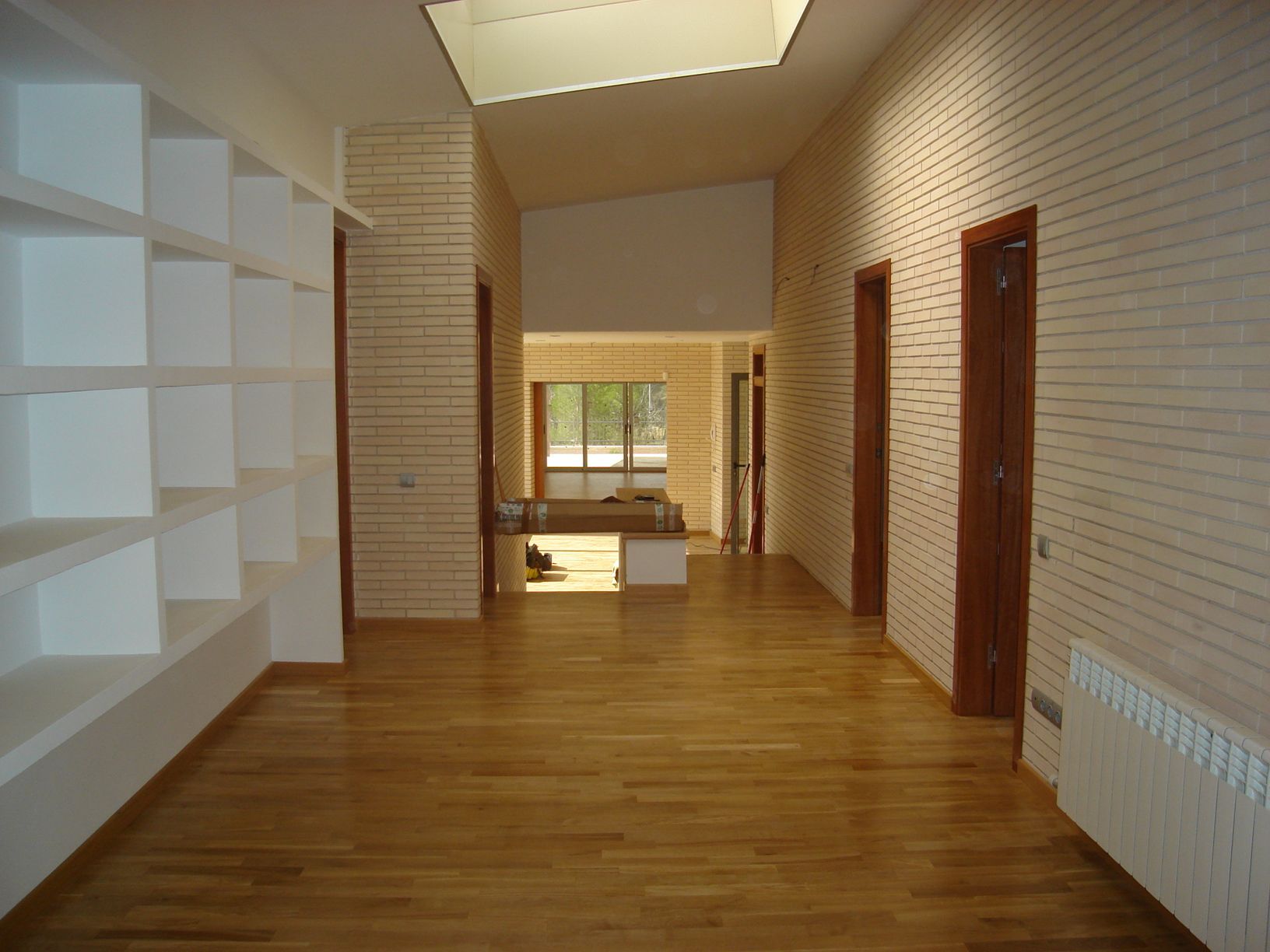 Un largo pasillo con pisos de madera y estantes blancos.