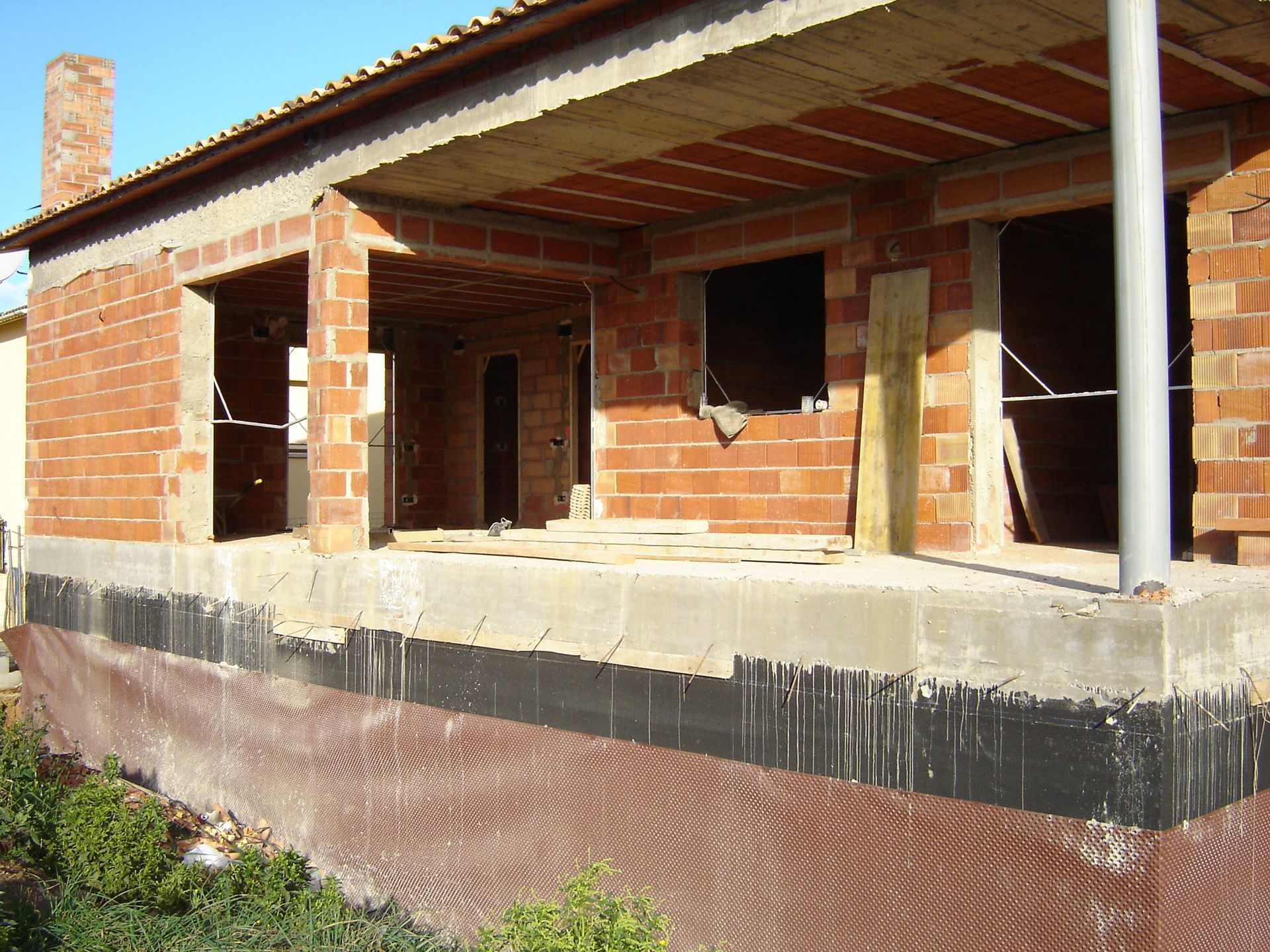 Una casa de ladrillo en construcción con porche y chimenea.
