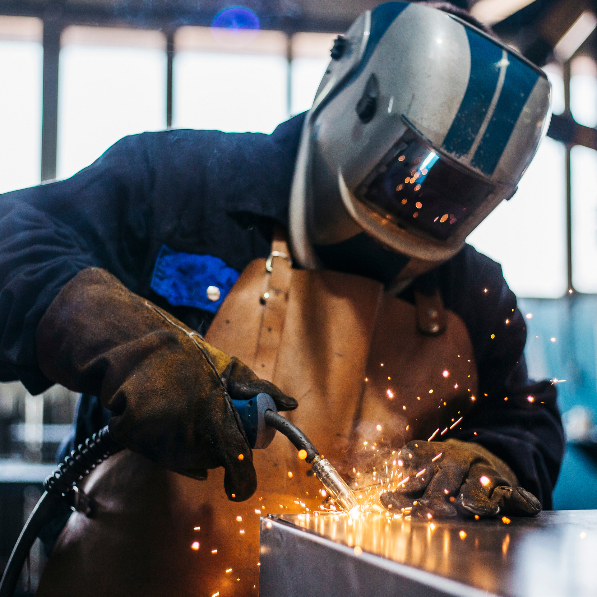 Un hombre que lleva un casco de soldadura está soldando una pieza de metal.