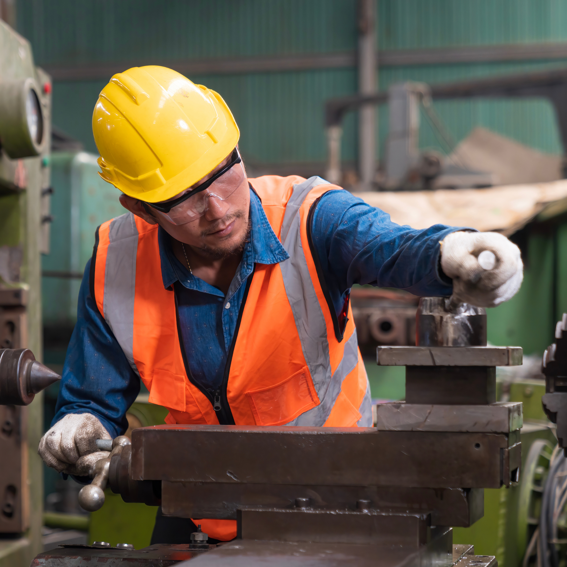 Un hombre que lleva casco y chaleco de seguridad está trabajando en una máquina.