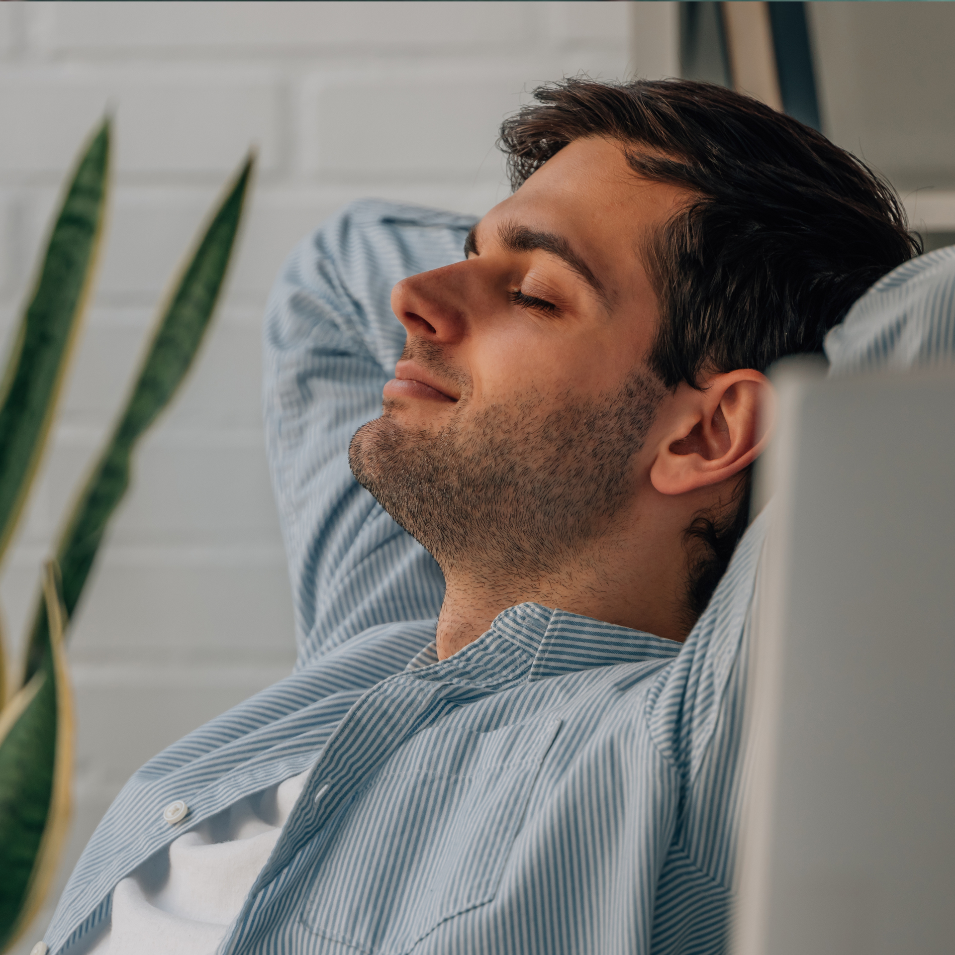 Un hombre con una camisa a rayas está acostado con los ojos cerrados.