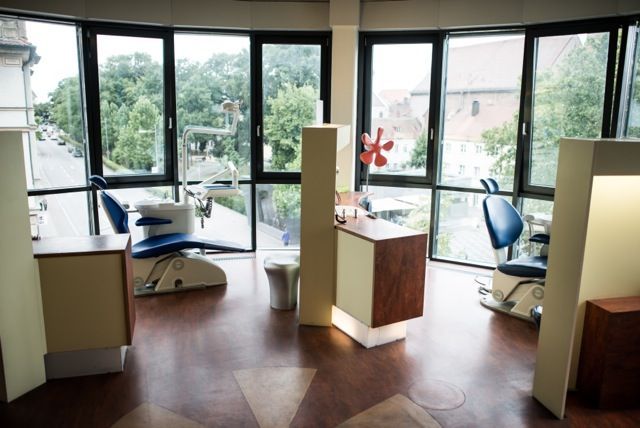 Modernes Büro mit blauen Stühlen, Schreibtischen, großen Fenstern und Holzboden.