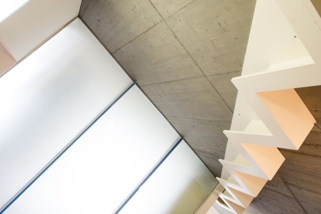 Abstrakte Ansicht von weißen geometrischen Deckenpaneelen und einer Betonwand