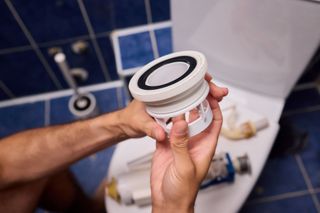 Sanitärwerkzeuge und -teile (Rohre, Armaturen, Schraubenschlüssel) auf einem Bauplan eines Hauses.