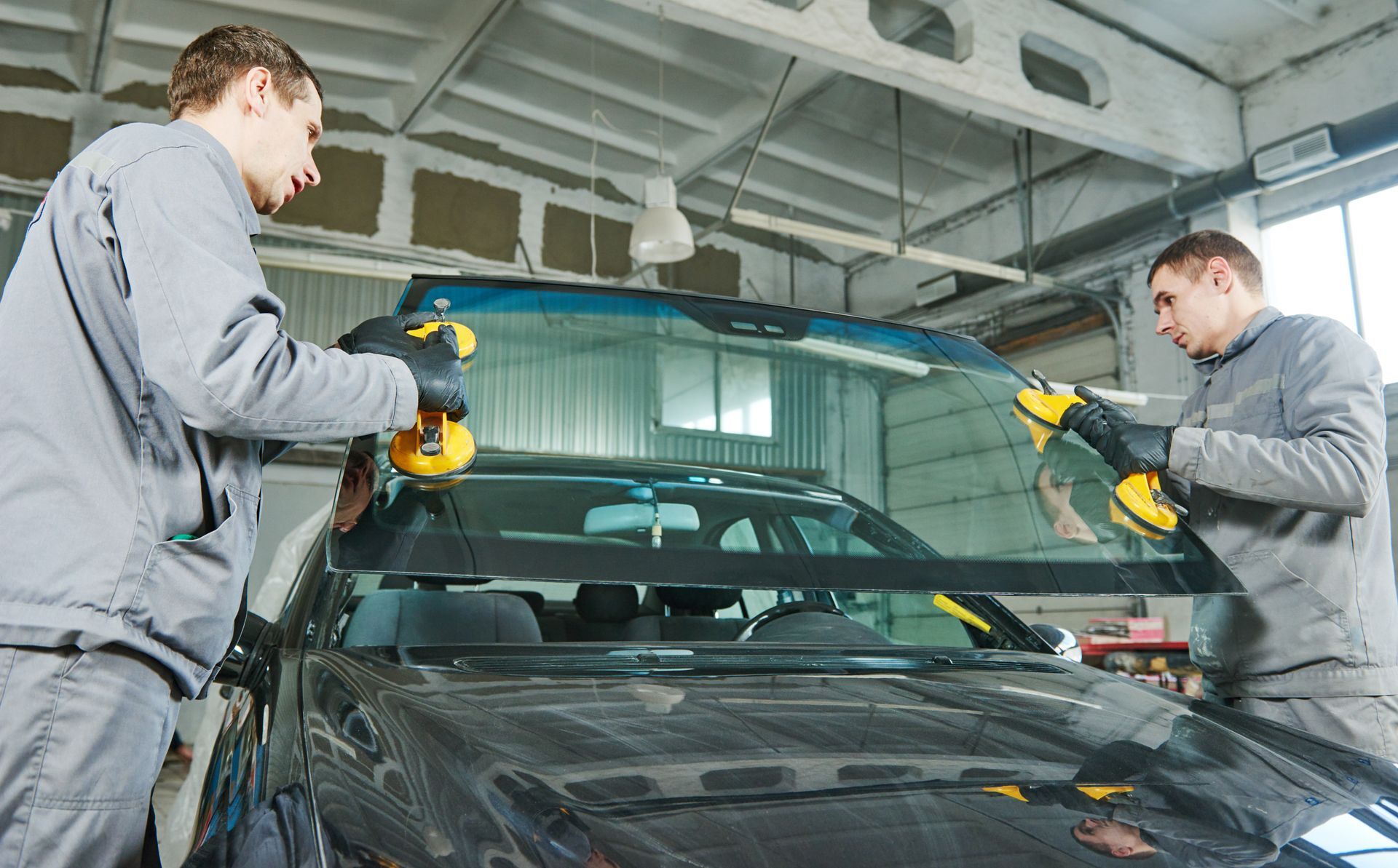 Deux ouvriers polissent une voiture à l'intérieur d'un atelier de réparation automobile.