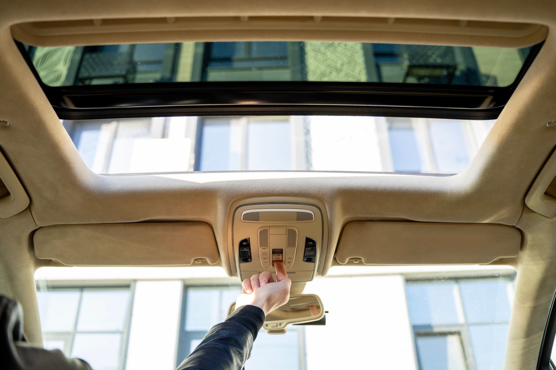 Réglage manuel des commandes de la console de pavillon et du toit ouvrant d'une voiture dans un intérieur.
