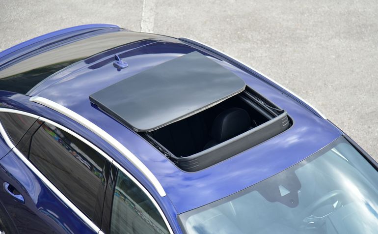 Voiture avec un panneau de toit ouvrant fermé et partiellement relevé sur le toit.
