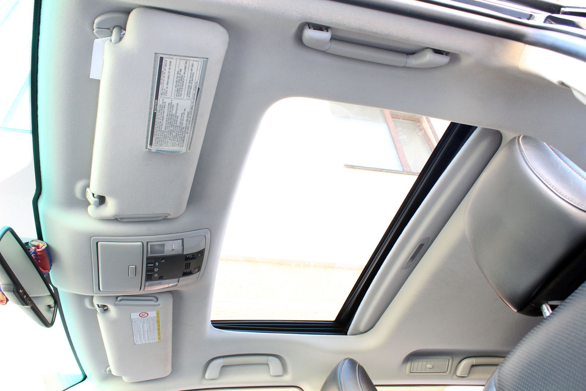 Intérieur de voiture avec toit ouvrant, pare-soleil et console de pavillon en sellerie.