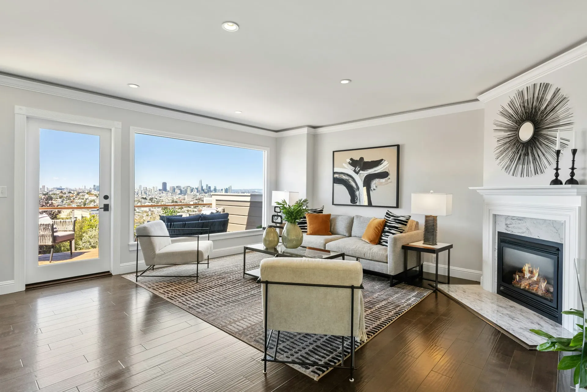 Sala de estar con grandes ventanales, vista a la ciudad, chimenea, sofá y muebles modernos.