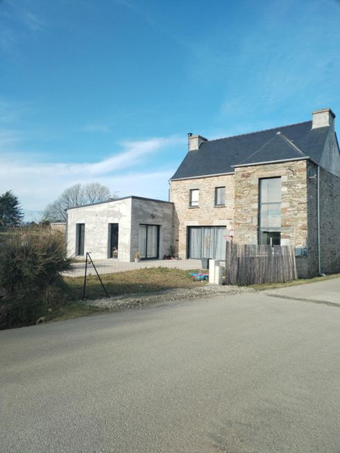 Maison en pierre et dépendance au bord d'une route tranquille.