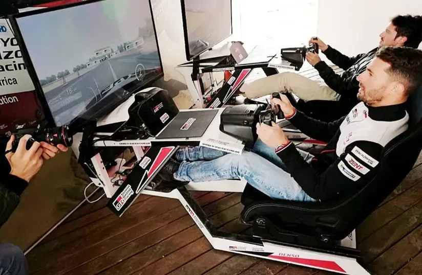 Las personas que utilizan simuladores de carreras en un entorno de juego se centran en pantallas grandes y volantes.